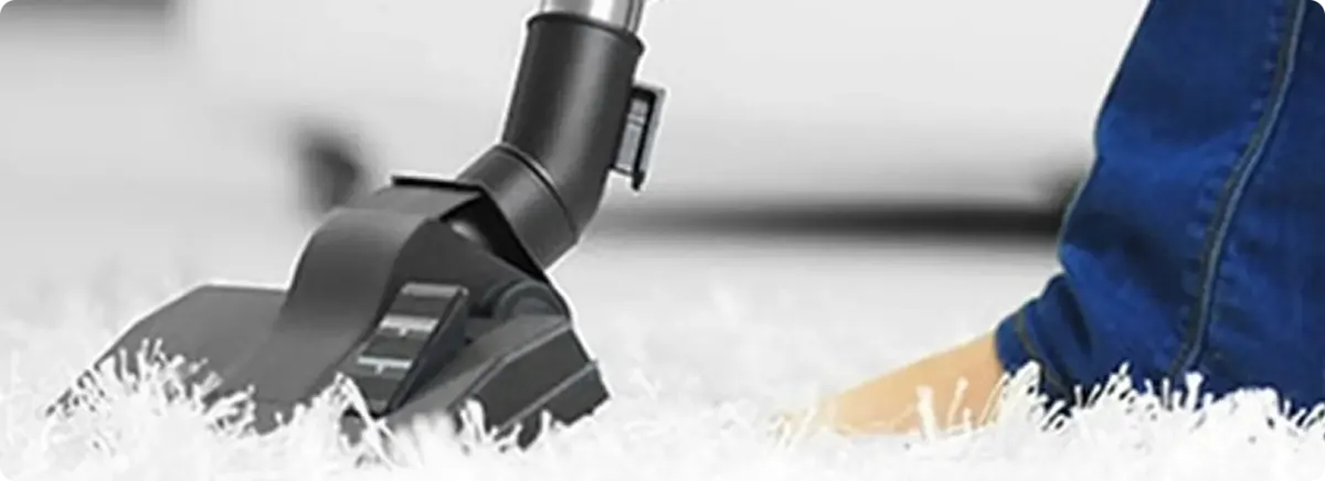Close-up of a professional vacuuming a white carpet in Jean.