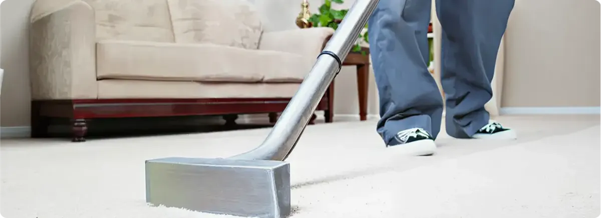 Carpet cleaning technician using a hot-water extraction wand on a light-colored carpet in a living room, Las Vegas, NV.